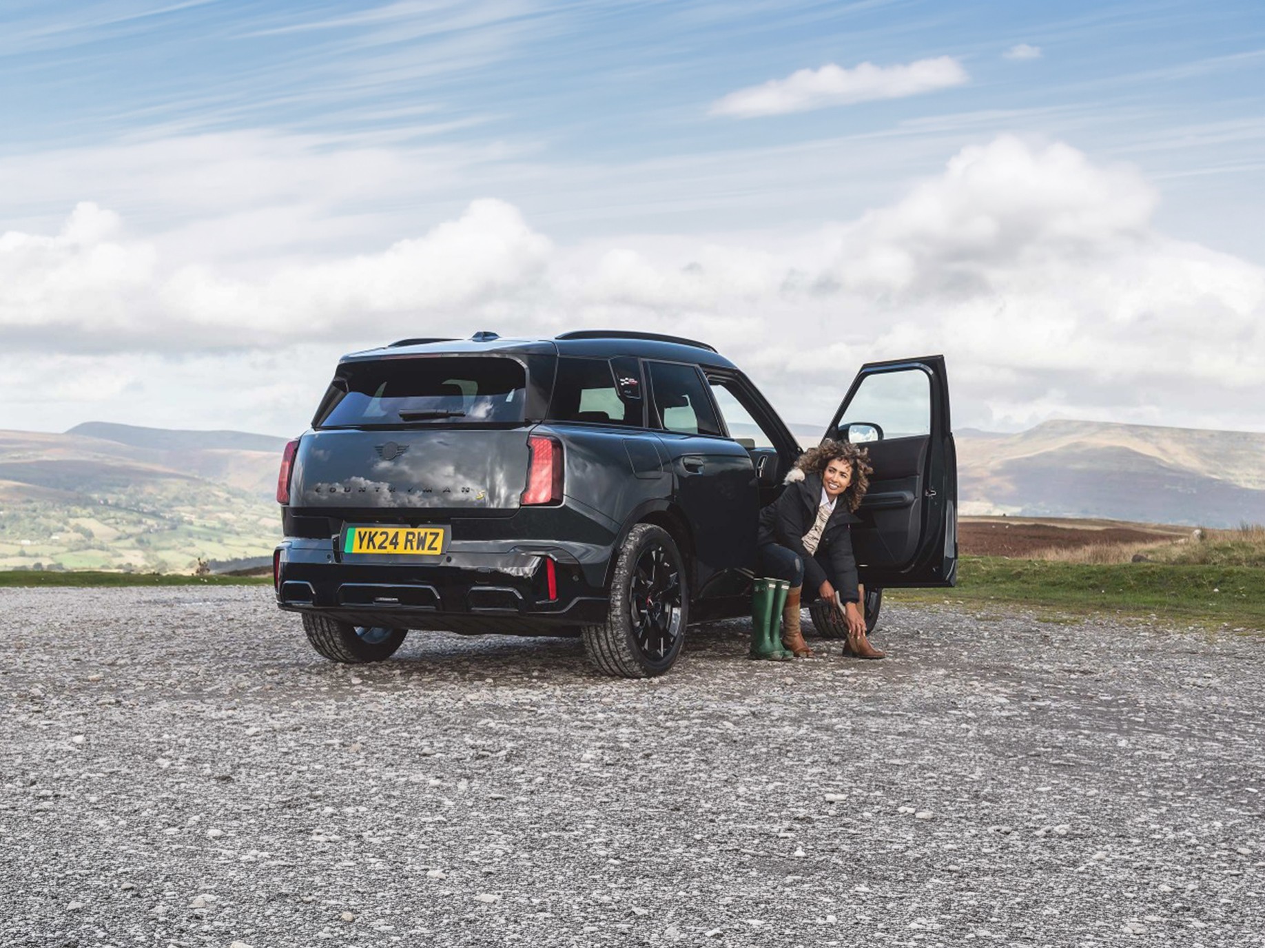 Rear view of the all-electric MINI Countryman in Smokey Green and Vibrant Silver roof parking. 